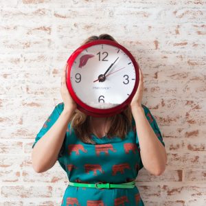 woman covering face using wall clock