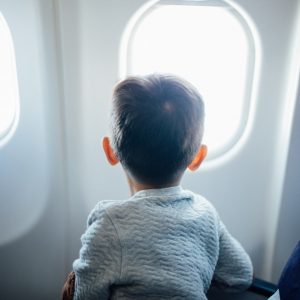 boy sitting on plane seat while viewing window