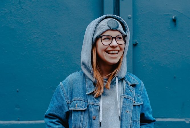 woman in blue jacket standing beside walls
