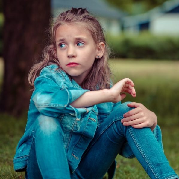 selective focus photography of girl sitting near tree