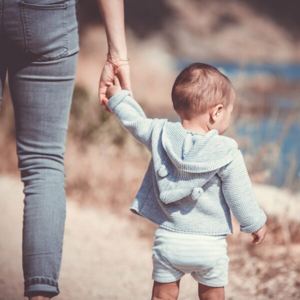 toddler's walking on the seashore with adult