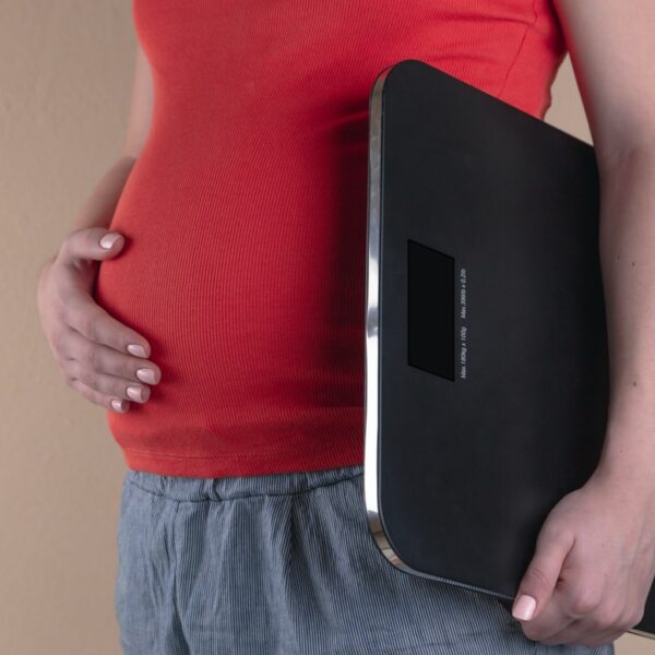 pregnant woman touching her belly and carrying a digital bathrooms cale