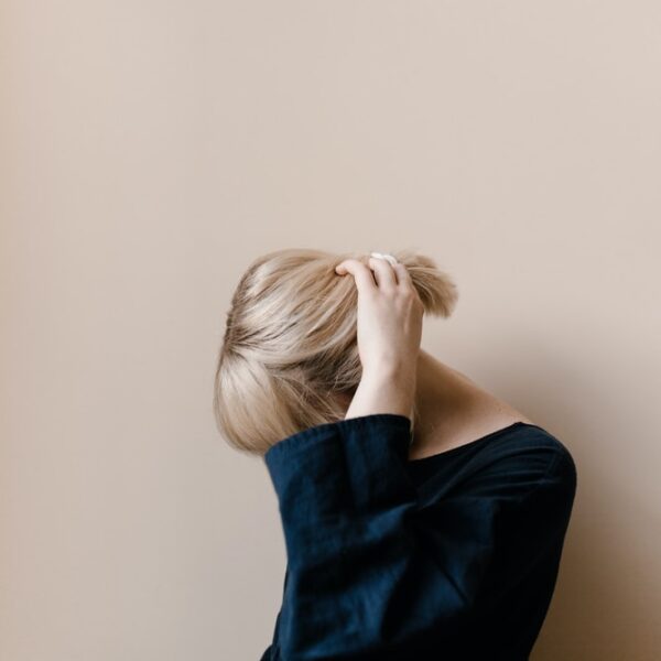 woman in blue shirt covering her face with her hair