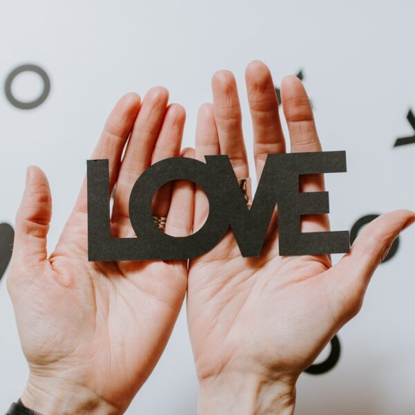 person holding love word cutout paper