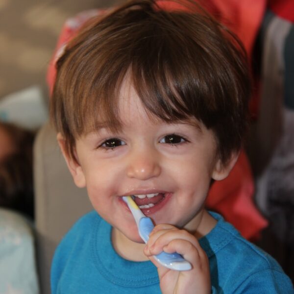 boy in blue crew neck shirt holding blue and white plastic toy