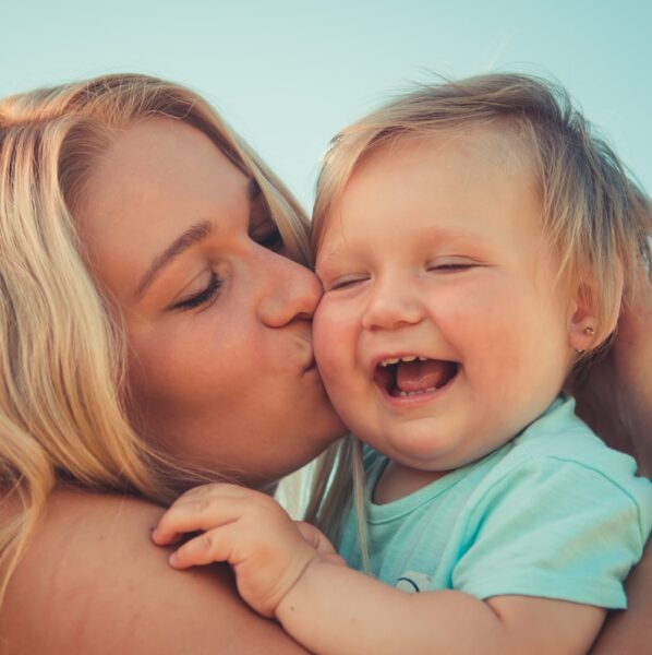 woman in teal shirt carrying girl in teal shirt