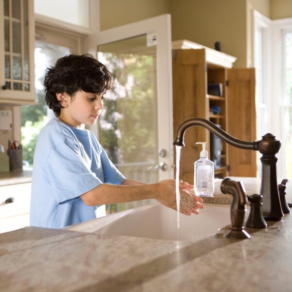 boy in blue polo shirt standing in front of sink