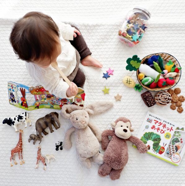boy sitting on white cloth surrounded by toys