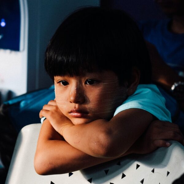 boy leaning on white chair