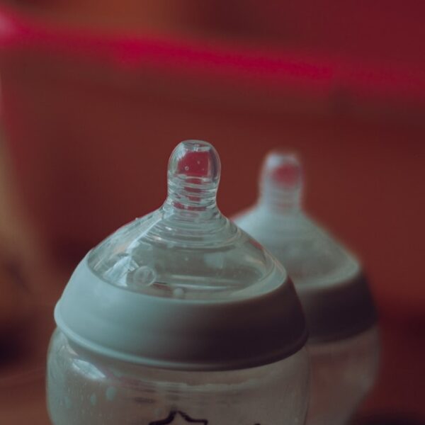 clear plastic feeding bottle on red table