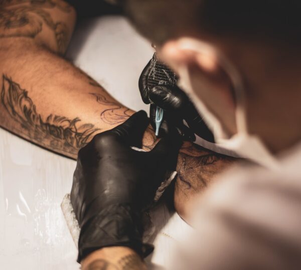 shallow focus photo of person tattooing person's right arm