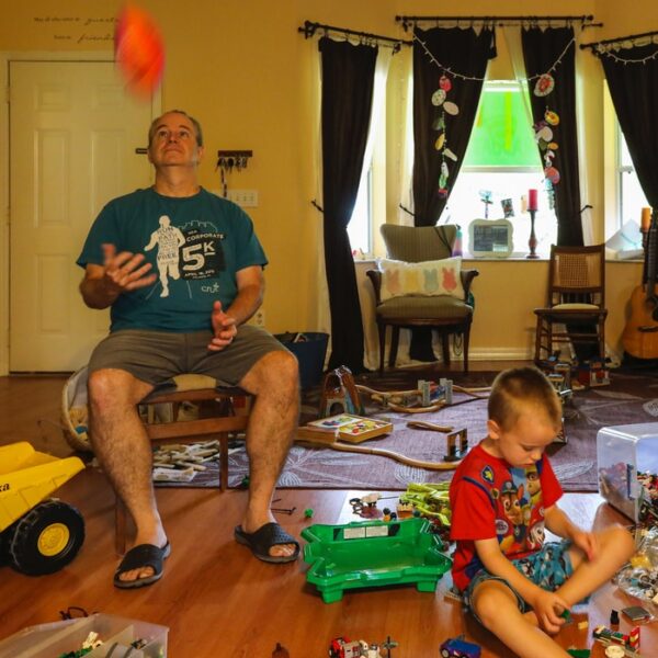 man in gray crew neck t-shirt sitting beside boy in red and white crew neck