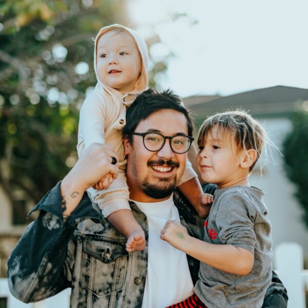 man in white shirt carrying girl in gray shirt