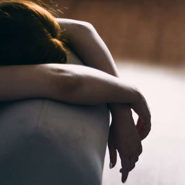 woman in black dress lying on gray couch