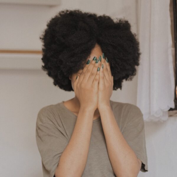 woman in gray t-shirt covering face with both hands