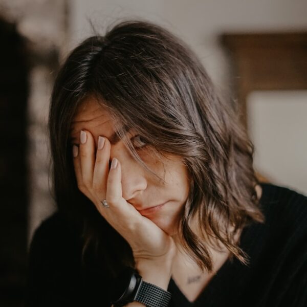 woman in black blazer covering her face