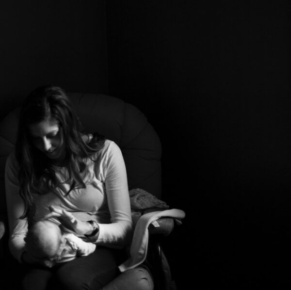 grayscale photo of woman holding a baby on her right hand while her left hand touching baby's face