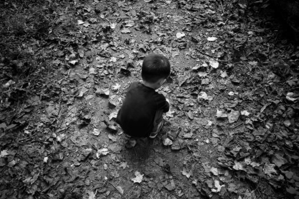 grayscale photo of child sitting on ground