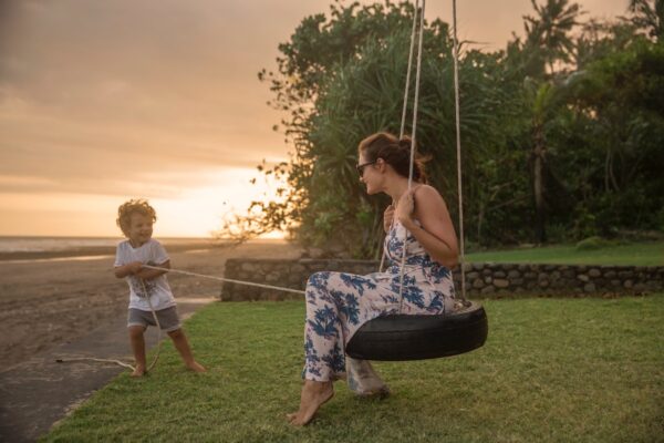 woman on tire swing pulled by boy