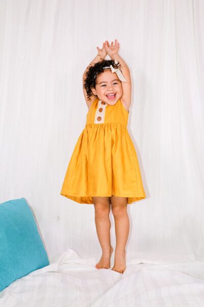 girl in yellow dress standing on blue chair