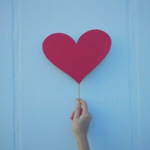 person holding heart shaped red balloon
