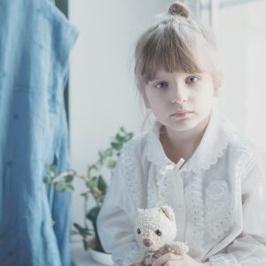 girl in white dress holding white bear plush toy